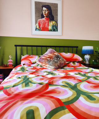 Colourful two tone bedroom in olive green and peach, with bold retro geometric printed Weirdstock bedding and a retro Miss Wong painting by Tretchikoff